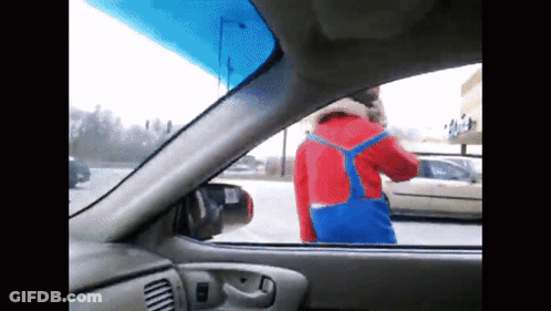 A Man In A Red And Blue Outfit Is Standing In A Parking Lot GIF