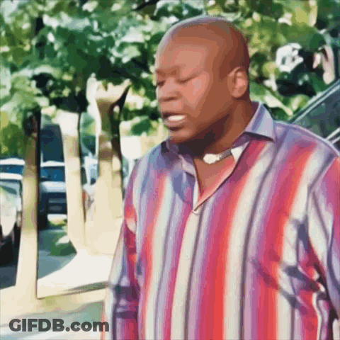 A Man In A Red And Blue Striped Shirt Stands On A Sidewalk GIF