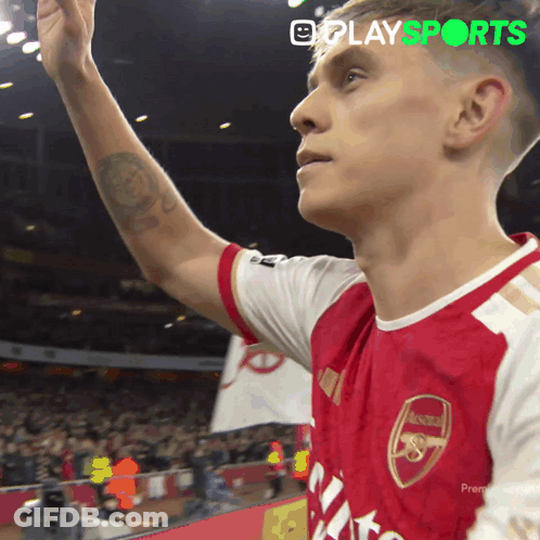 A Man In A Red And White Arsenal Jersey Waves His Hand GIF