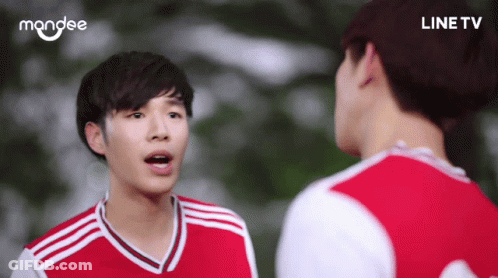 A Man In A Red And White Jersey Is Talking To Another Man In A Line Tv Ad GIF