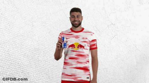 A Man In A Red And White Red Bull Shirt Holds A Red Bull Can GIF