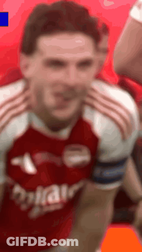 A Man In A Red And White Soccer Jersey Is Making A Face . GIF