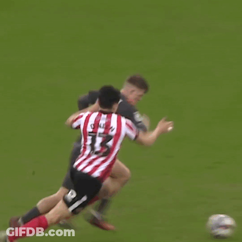 A Man In A Red And White Striped Shirt Is Hugging Another Man In A Black Shirt On A Soccer Field . GIF
