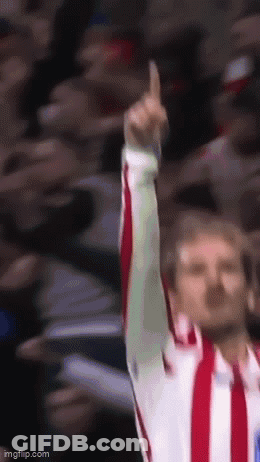 A Man In A Red And White Striped Shirt Is Raising His Finger Up In The Air GIF