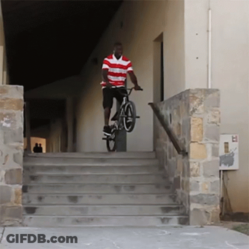 A Man In A Red And White Striped Shirt Is Riding A Bike Down Some Stairs GIF