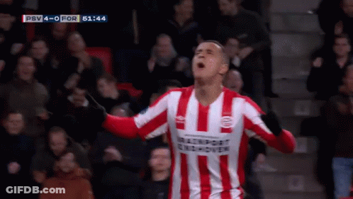 A Man In A Red And White Striped Shirt Is Standing In Front Of A Soccer Goal . GIF