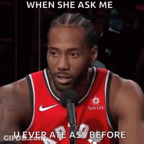 A Man In A Red Basketball Jersey Is Talking Into A Microphone . GIF