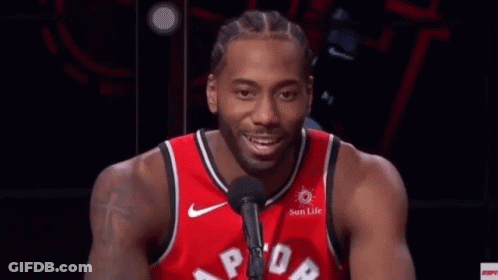 A Man In A Red Basketball Jersey Is Talking Into A Microphone . GIF