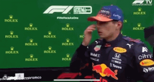 A Man In A Red Bull Racing Outfit Is Covering His Nose . GIF