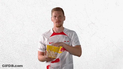 A Man In A Red Bull Shirt Holds A Bowl Of Popcorn GIF