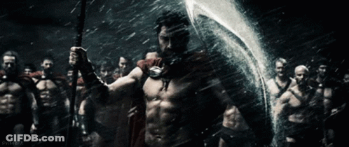 A Man In A Red Cape Is Holding A Spear And Shield In Front Of A Group Of Men GIF