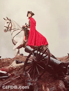 A Man In A Red Cape Is Riding A White Horse Next To A Cannon GIF