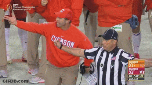 A Man In A Red Clemson Sweatshirt Stands Next To An Umpire GIF