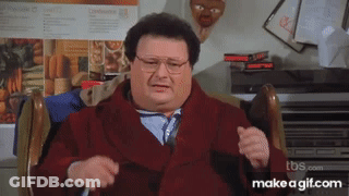 A Man In A Red Coat And Tie Is Sitting In A Chair .. GIF