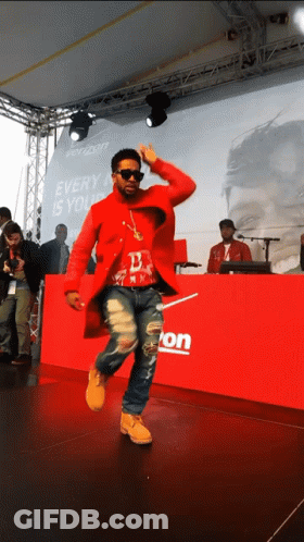 A Man In A Red Coat Is Dancing In Front Of A Verizon Sign GIF