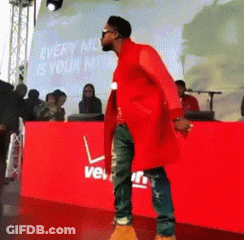 A Man In A Red Coat Is Standing In Front Of A Red Verizon Sign GIF