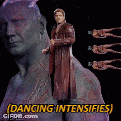 A Man In A Red Coat Is Standing In Front Of A Statue With The Words Dancing Intensifies Below Him GIF