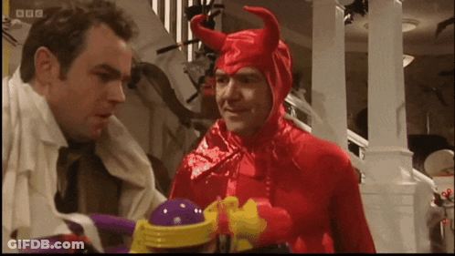 A Man In A Red Devil Costume Talks To Another Man In A White Shirt GIF