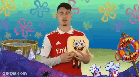 A Man In A Red Emirates Jersey Holds A Stuffed Spongebob Doll GIF