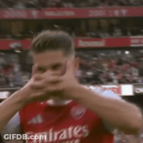 A Man In A Red Emirates Jersey Is Covering His Face With His Hands . GIF