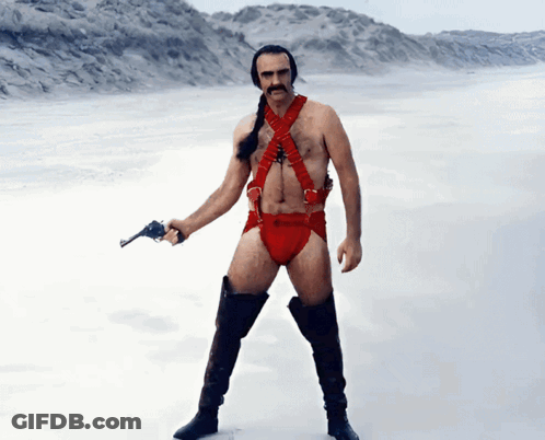 A Man In A Red Harness And Boots Holds A Gun GIF