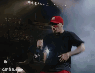 A Man In A Red Hat And Black Shirt Is Dancing On A Stage GIF