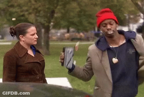 A Man In A Red Hat Is Smoking A Cigarette While Standing Next To A Woman GIF