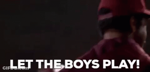 A Man In A Red Hat Is Standing In Front Of A Sign That Says `` Let The Boys Play ! '' GIF