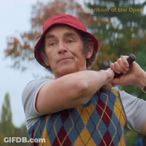 A Man In A Red Hat Is Swinging A Golf Club With The Words Phantom Of The Open Above Him GIF