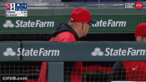 A Man In A Red Hat Sits In A Dugout With State Farm Advertisements GIF