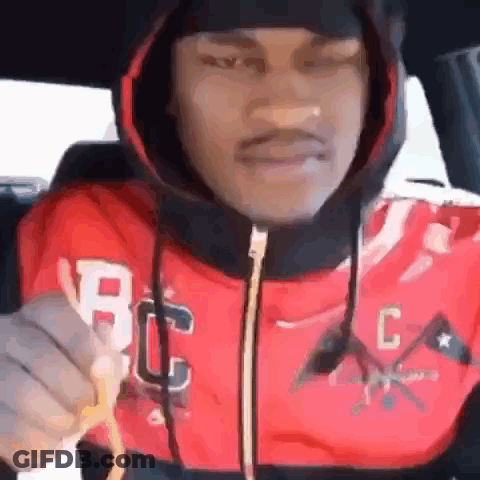 A Man In A Red Hoodie Is Holding A French Fry In His Hand . GIF