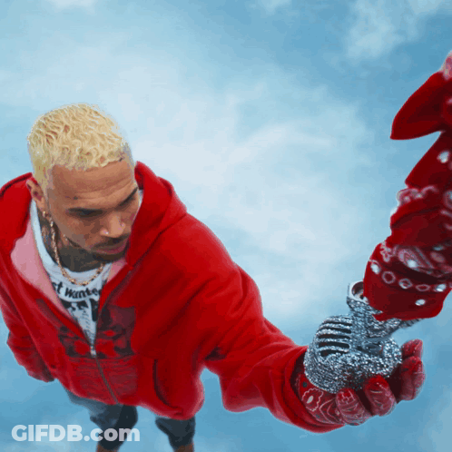A Man In A Red Hoodie Is Holding A Microphone In His Hand GIF