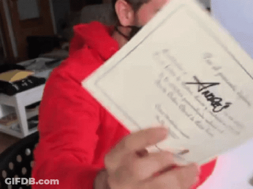 A Man In A Red Hoodie Is Holding A Piece Of Paper With The Name Angel Written On It GIF