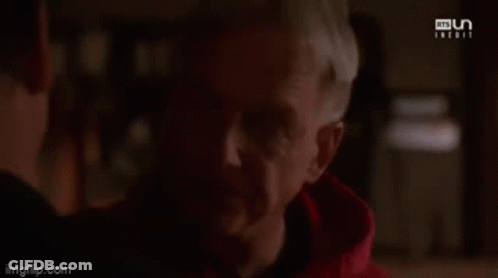 A Man In A Red Hoodie Is Looking At Another Man . GIF