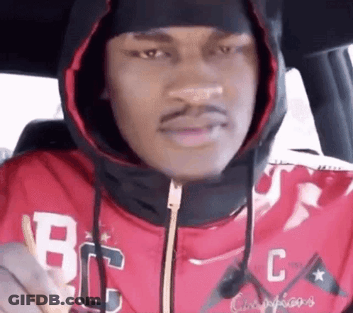 A Man In A Red Hoodie Is Sitting In The Back Seat Of A Car . GIF
