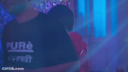 A Man In A Red Hoodie Is Standing In Front Of A Neon Ring GIF