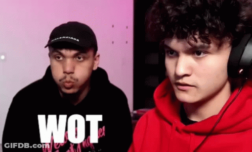 A Man In A Red Hoodie Is Standing Next To Another Man In A Black Hat . GIF