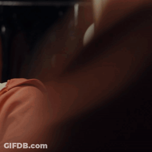 A Man In A Red Hoodie Looks At Himself In The Mirror GIF