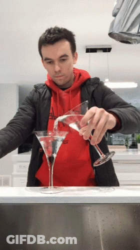 A Man In A Red Hoodie Pours A Martini Into Two Glasses GIF