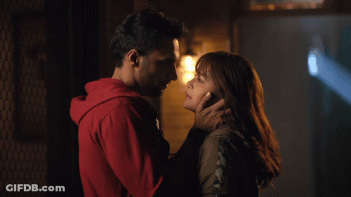 A Man In A Red Hoodie Touches A Woman 'S Forehead GIF