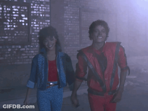 A Man In A Red Jacket And A Woman In A Blue Jacket Are Dancing GIF