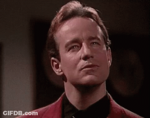 A Man In A Red Jacket And Black Tie Is Making A Face With His Eyes Closed . GIF