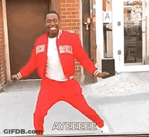 A Man In A Red Jacket And Pants Is Dancing In Front Of A Building . GIF