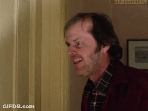 A Man In A Red Jacket And Plaid Shirt Is Standing In A Doorway And Smiling . GIF