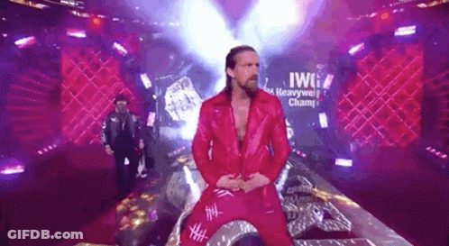 A Man In A Red Jacket And Red Pants Is Standing On A Stage In Front Of A Sign That Says Heavyweight Champion . GIF
