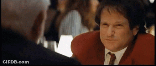 A Man In A Red Jacket And Tie Is Talking To Another Man In A Restaurant . GIF