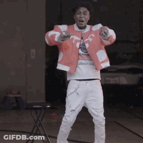 A Man In A Red Jacket And White Pants Is Standing In Front Of A Table GIF