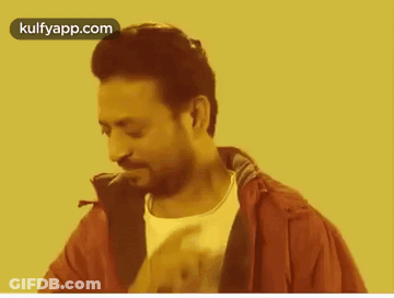 A Man In A Red Jacket And White Shirt Is Smoking A Cigarette On A Yellow Background . GIF