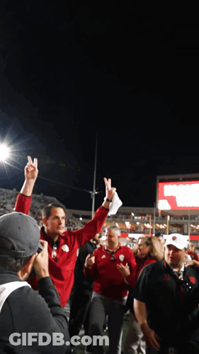 A Man In A Red Jacket Holds Up His Index Finger In The Air GIF