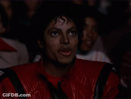 A Man In A Red Jacket Is Clapping His Hands In A Crowd GIF